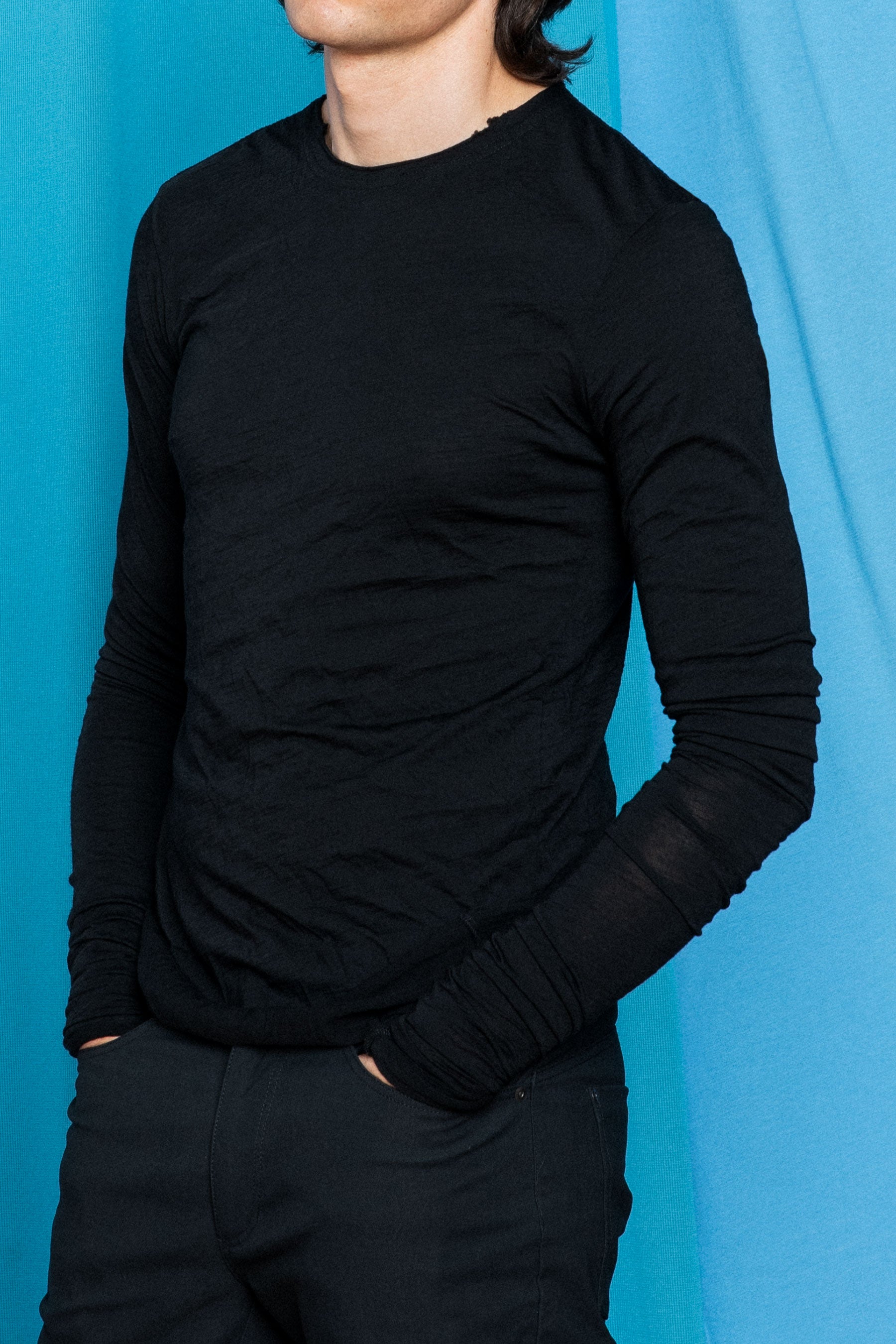 Waist-up image of Daniele wearing the Dreamweight Rawcut Longsleeve in Black with his hands in his pockets.