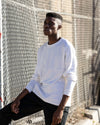 Edem standing in front of a chain link fence while wearing the Experiment 252 - Cottonweight Billboard in Washed White